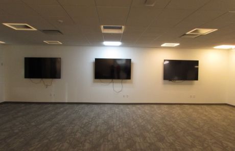 A room with three flat screen tvs on the wall