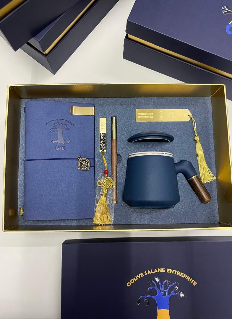 Une boîte bleue avec une tasse, un cahier et un stylo à l'intérieur.