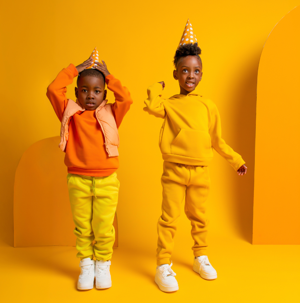 Deux jeunes garçons portant des chapeaux de fête se tiennent l'un à côté de l'autre sur un fond jaune.