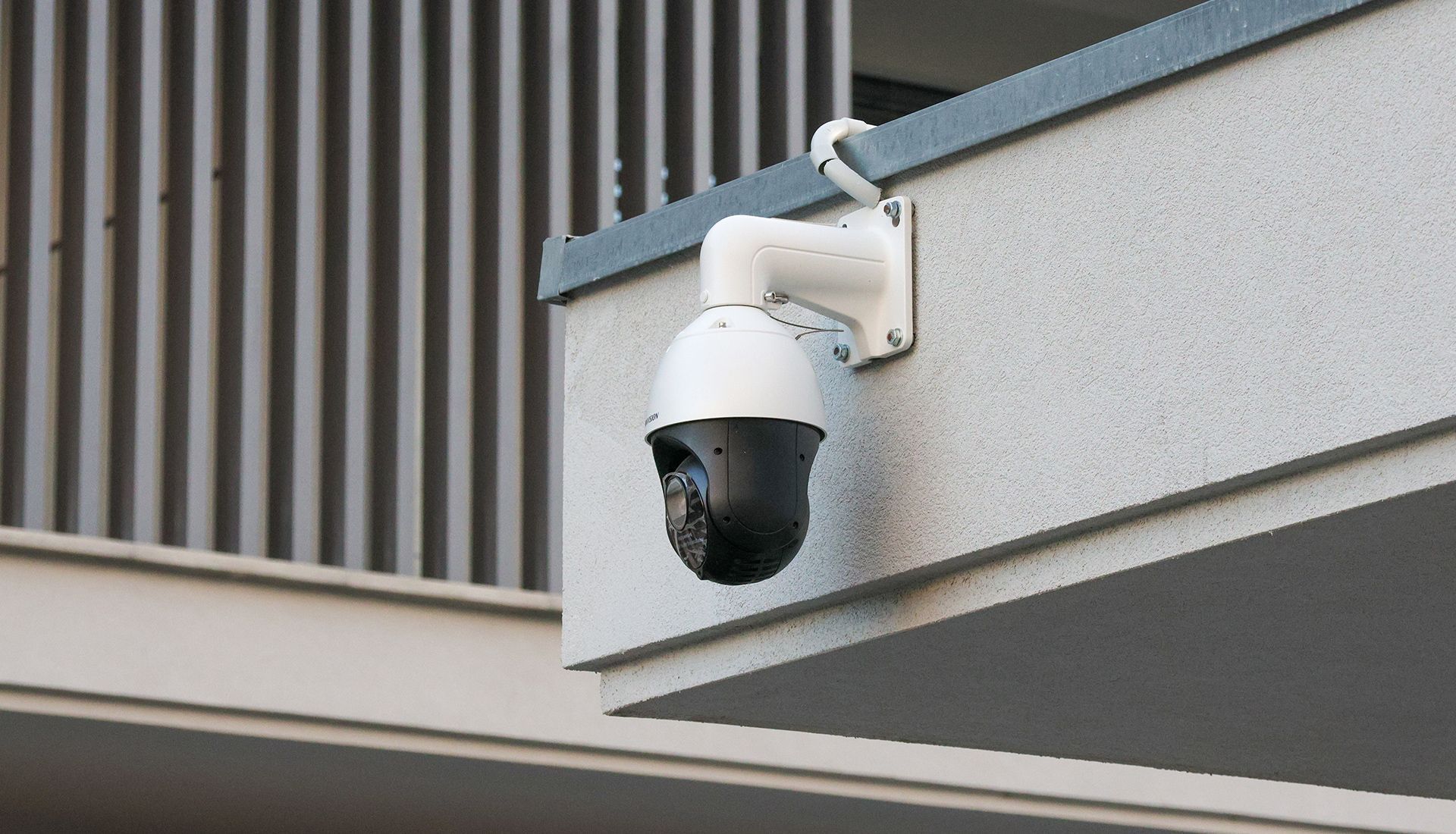 Security camera mounted on a building's exterior, white and black colors.
