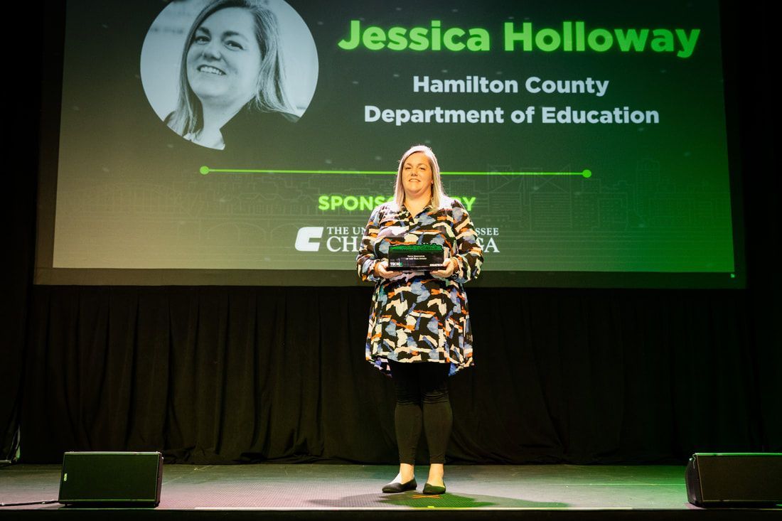A woman is standing on a stage in front of a large screen.