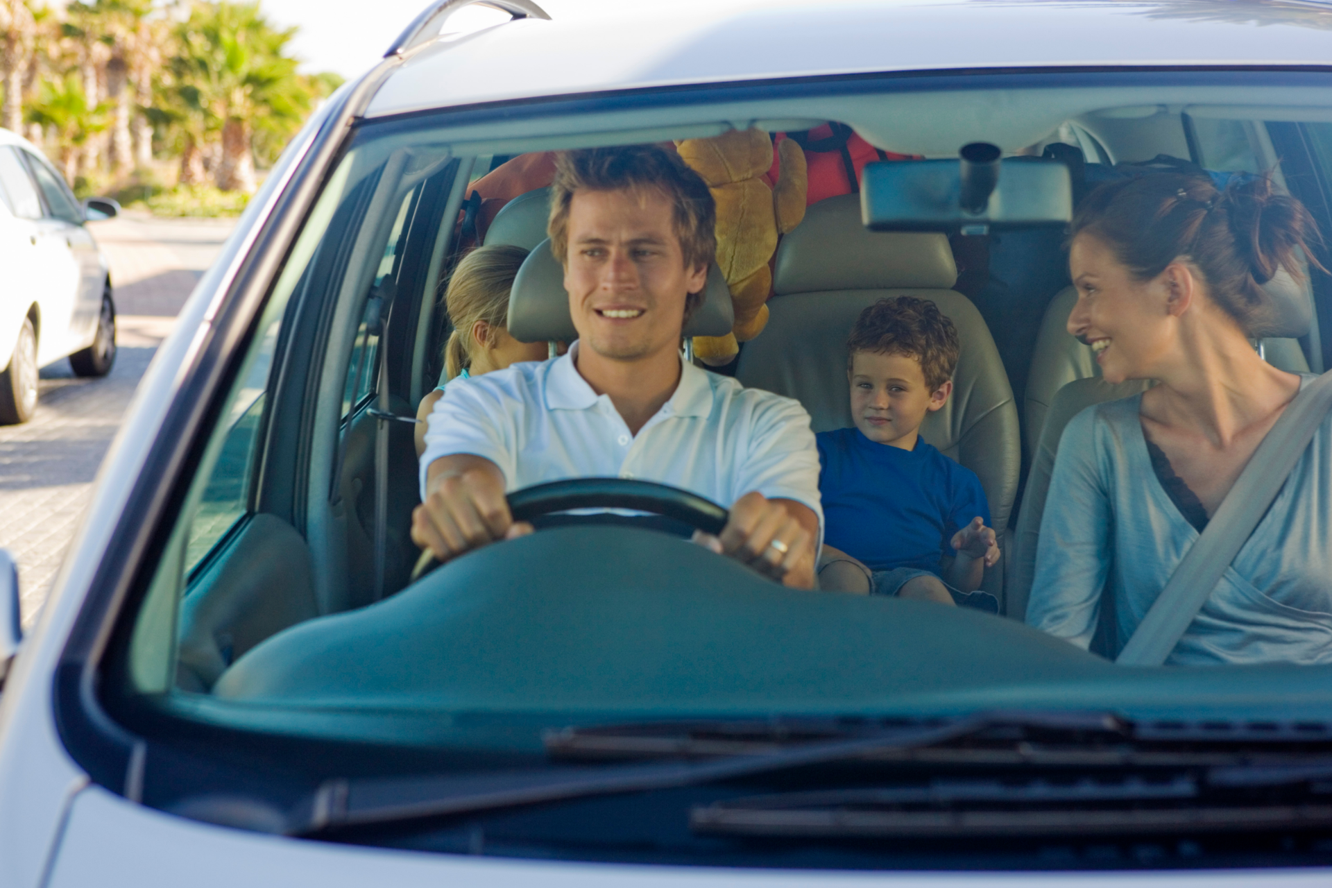 Mechanic working on the underside of a car lifted on a platform in a garage.