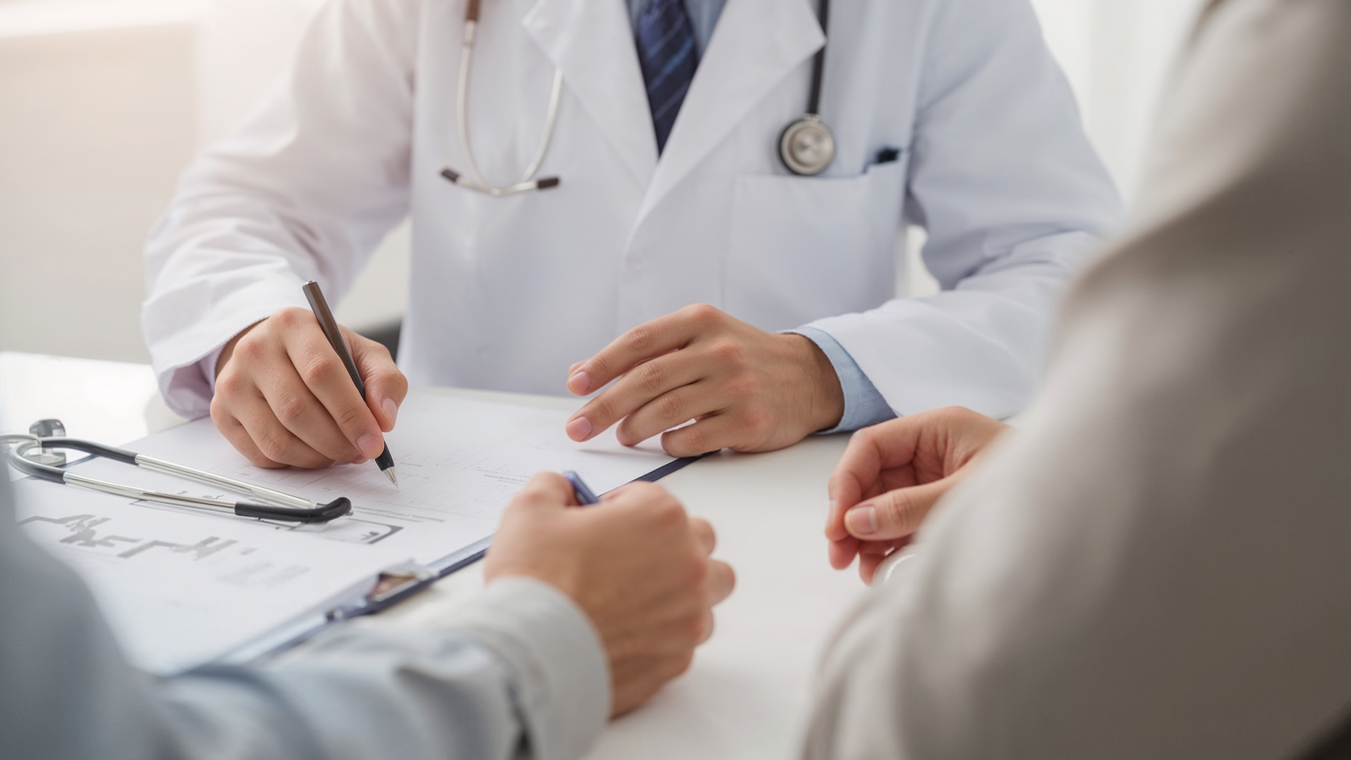 Blue car driving along a coastal road lined with palm trees under a bright blue sky.