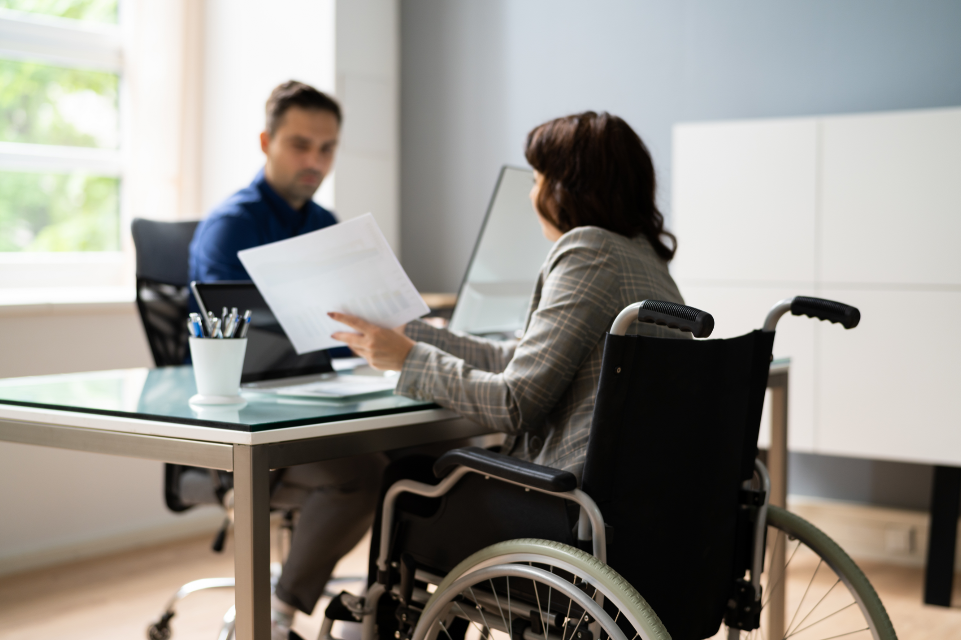White apartment building with balconies, construction fence in front, blue sky.