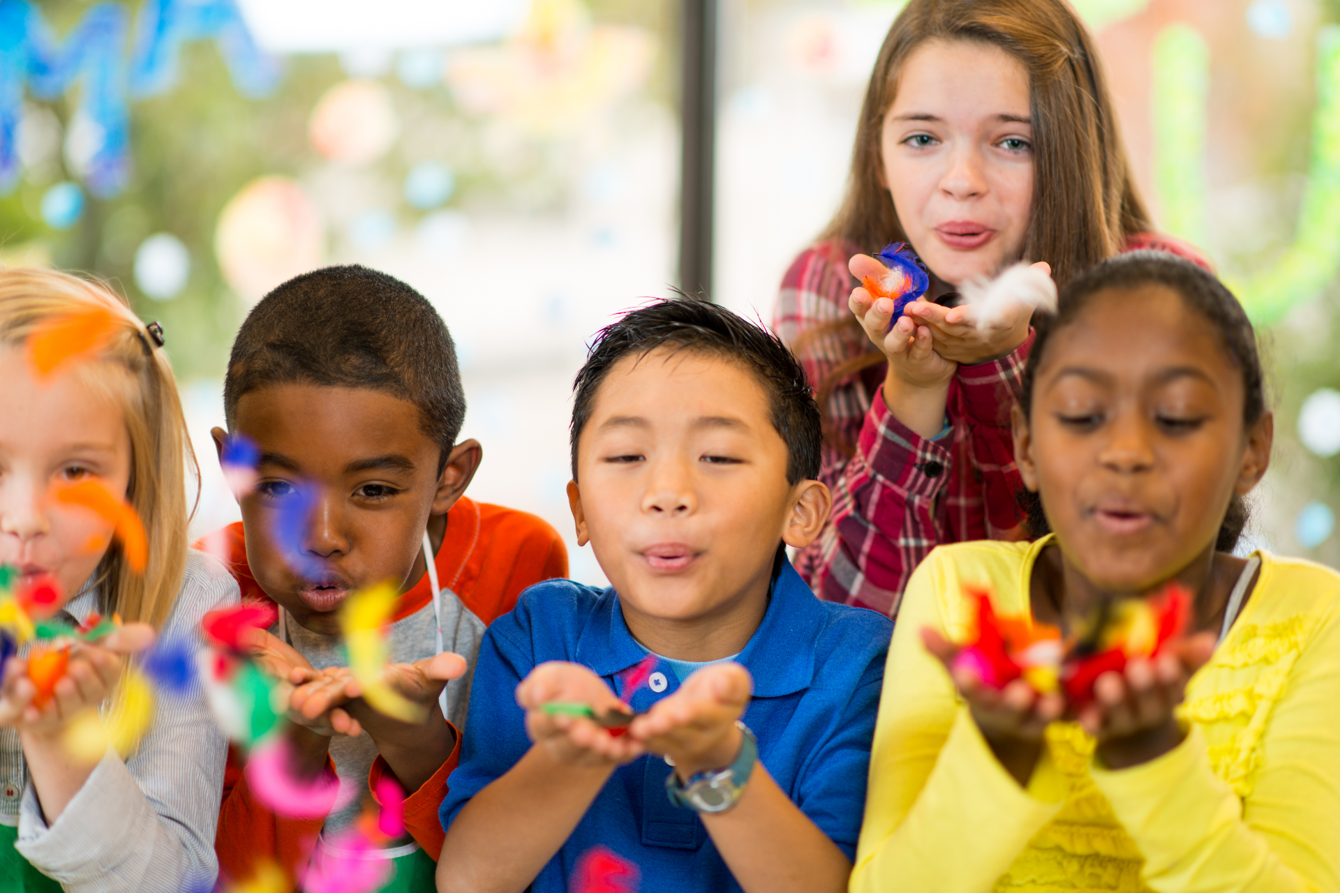 Woman packing a cardboard box, smiling. Boxes and another person nearby, in a room, light setting.