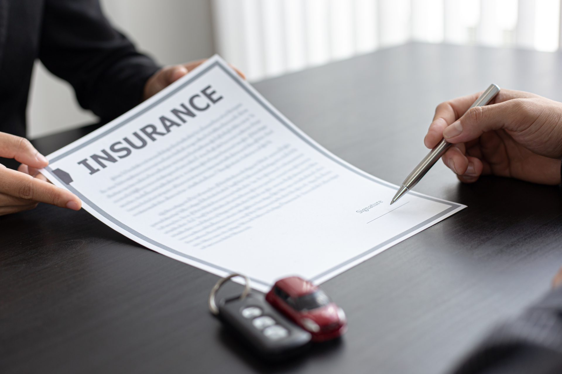 Mechanic working on the underside of a car lifted on a platform in a garage.