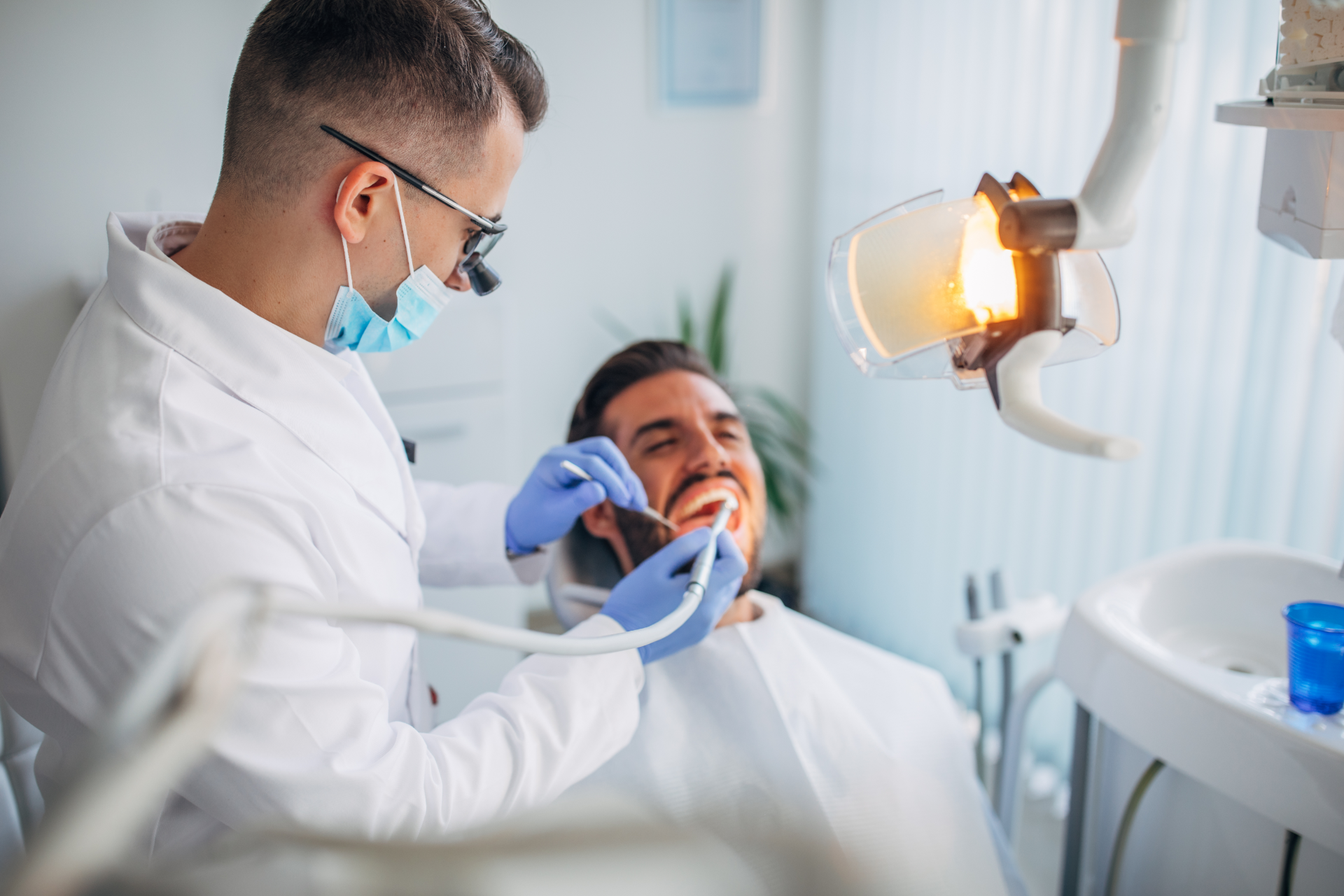 White apartment building with balconies, construction fence in front, blue sky.