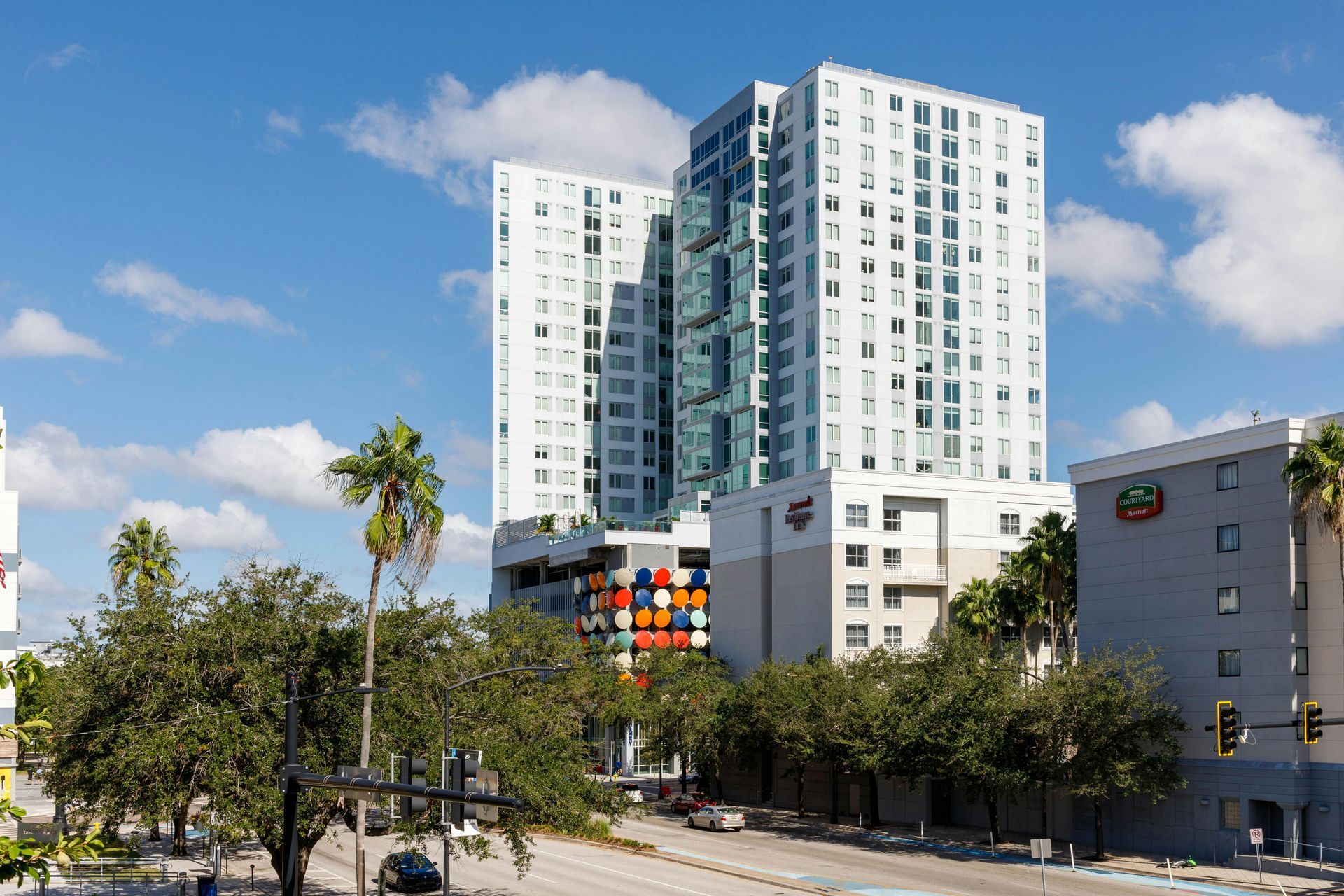 Skyscrapers and buildings under a blue sky with trees lining a street in Miami.