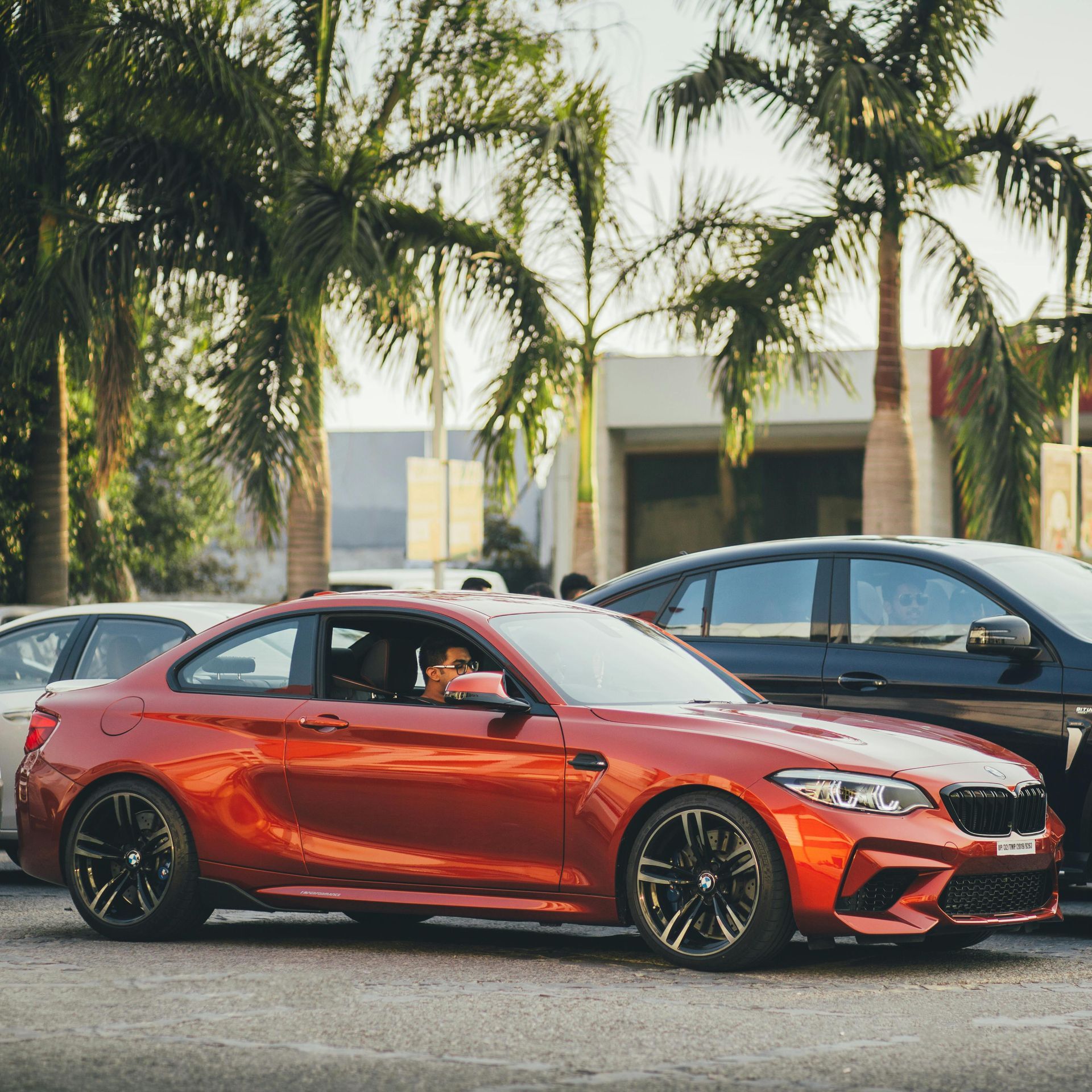Two-story light green house with a white balcony and roof, on a gravel driveway under a clear blue sky.