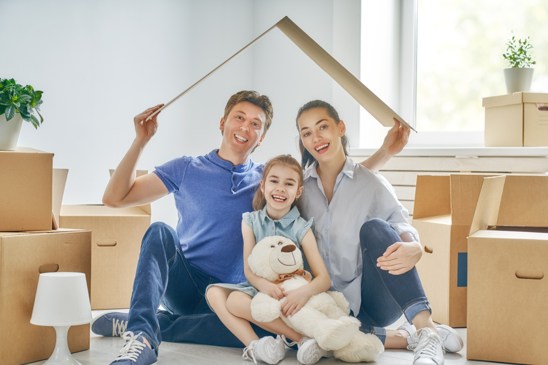 Mechanic working on the underside of a car lifted on a platform in a garage.