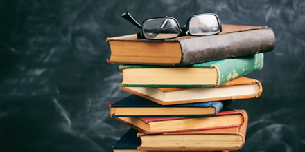 Stapel boeken met een bril er bovenop.