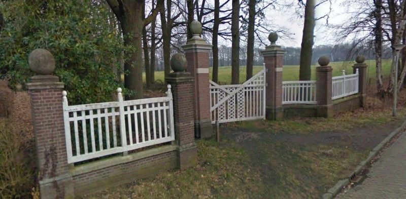 Op een kier geopende toegangspoort tot oud landgoed.