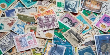 Verzameling postzeges verspreid over een tafel.