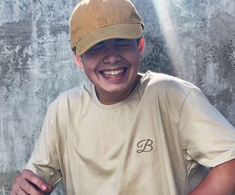 Una persona sostiene una pila de camisetas con la letra b.