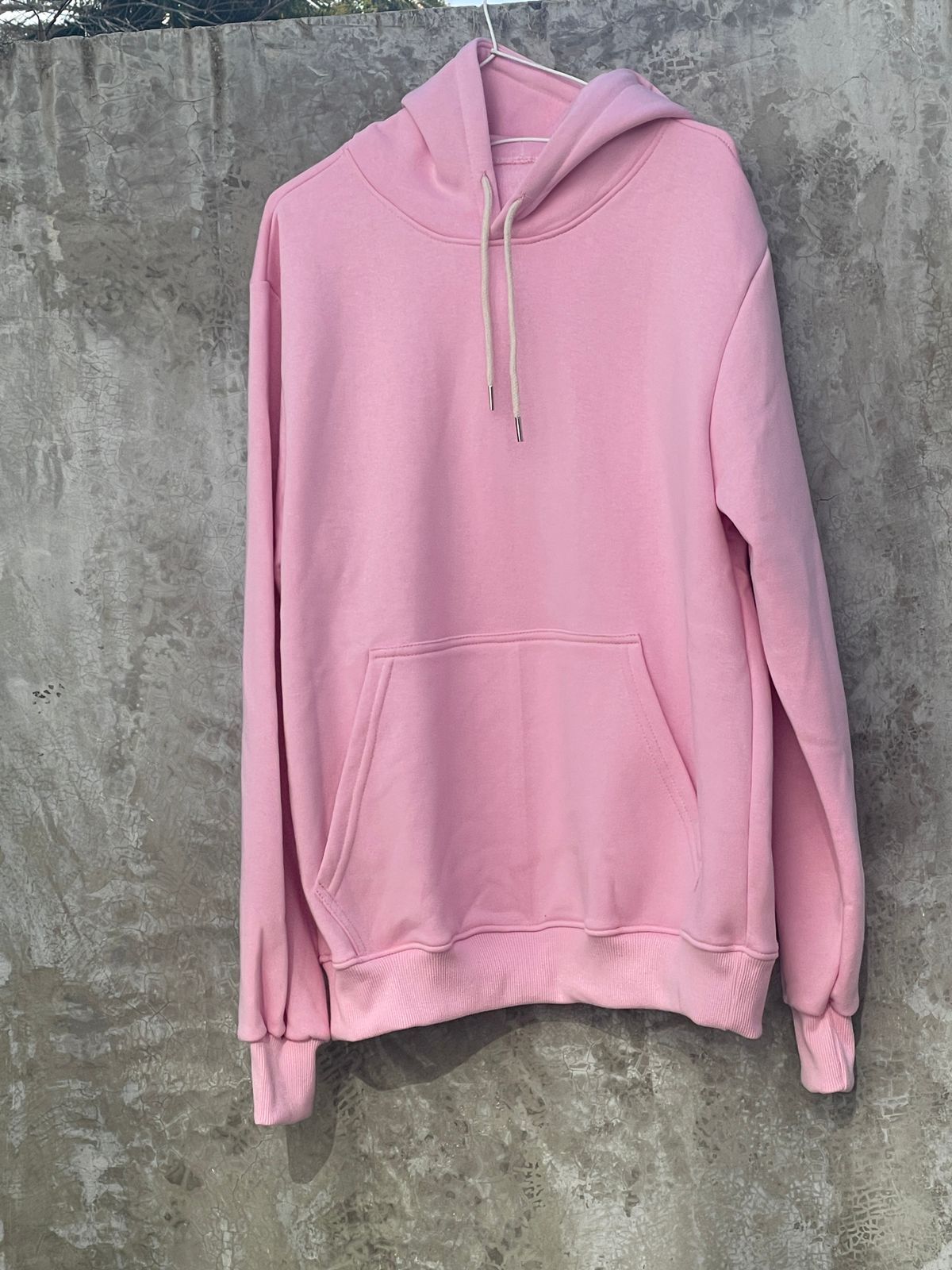 Una sudadera con capucha rosa está colgada en una percha.