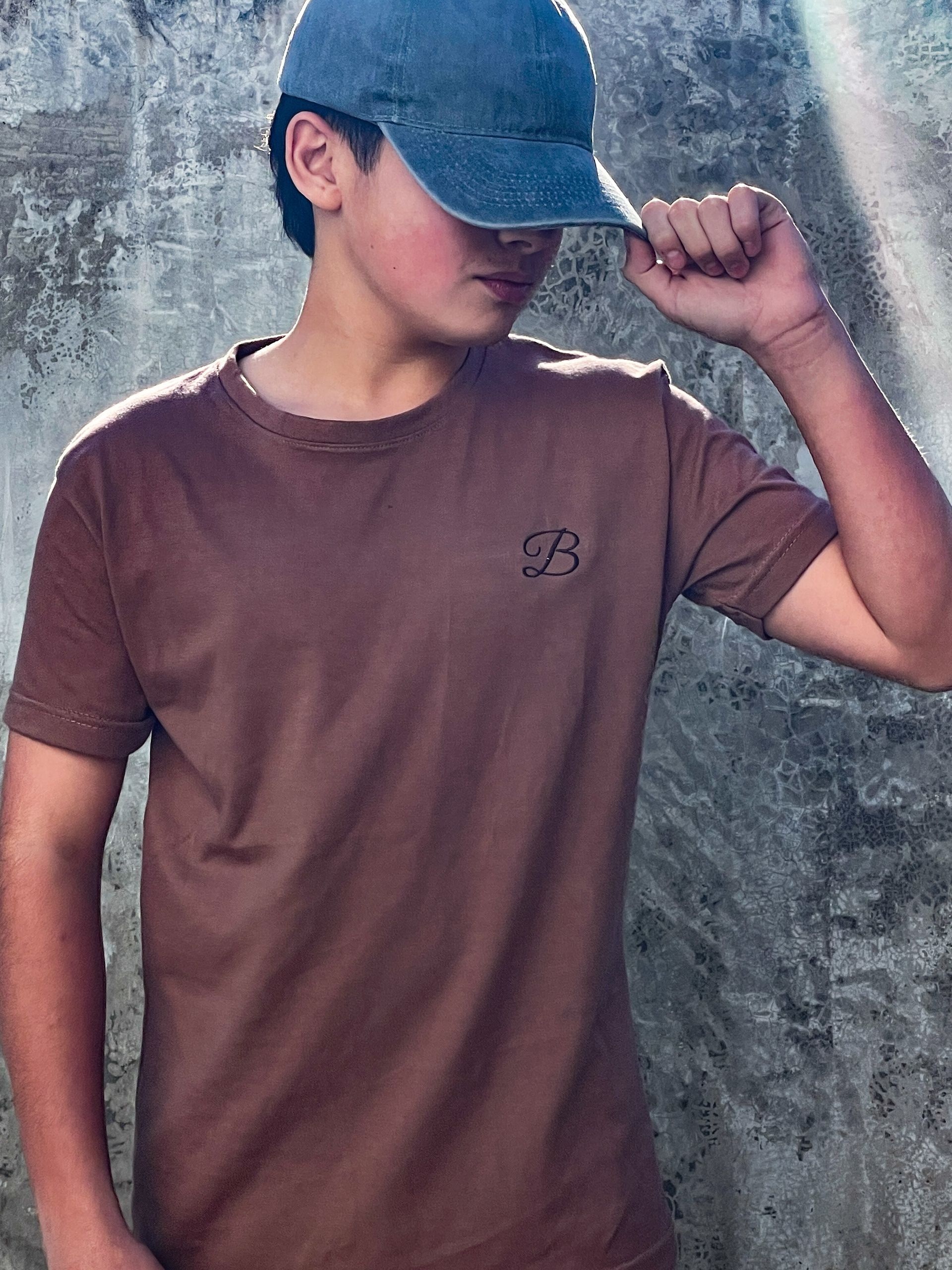 Un niño que lleva un sombrero y una camisa marrón con la letra b.