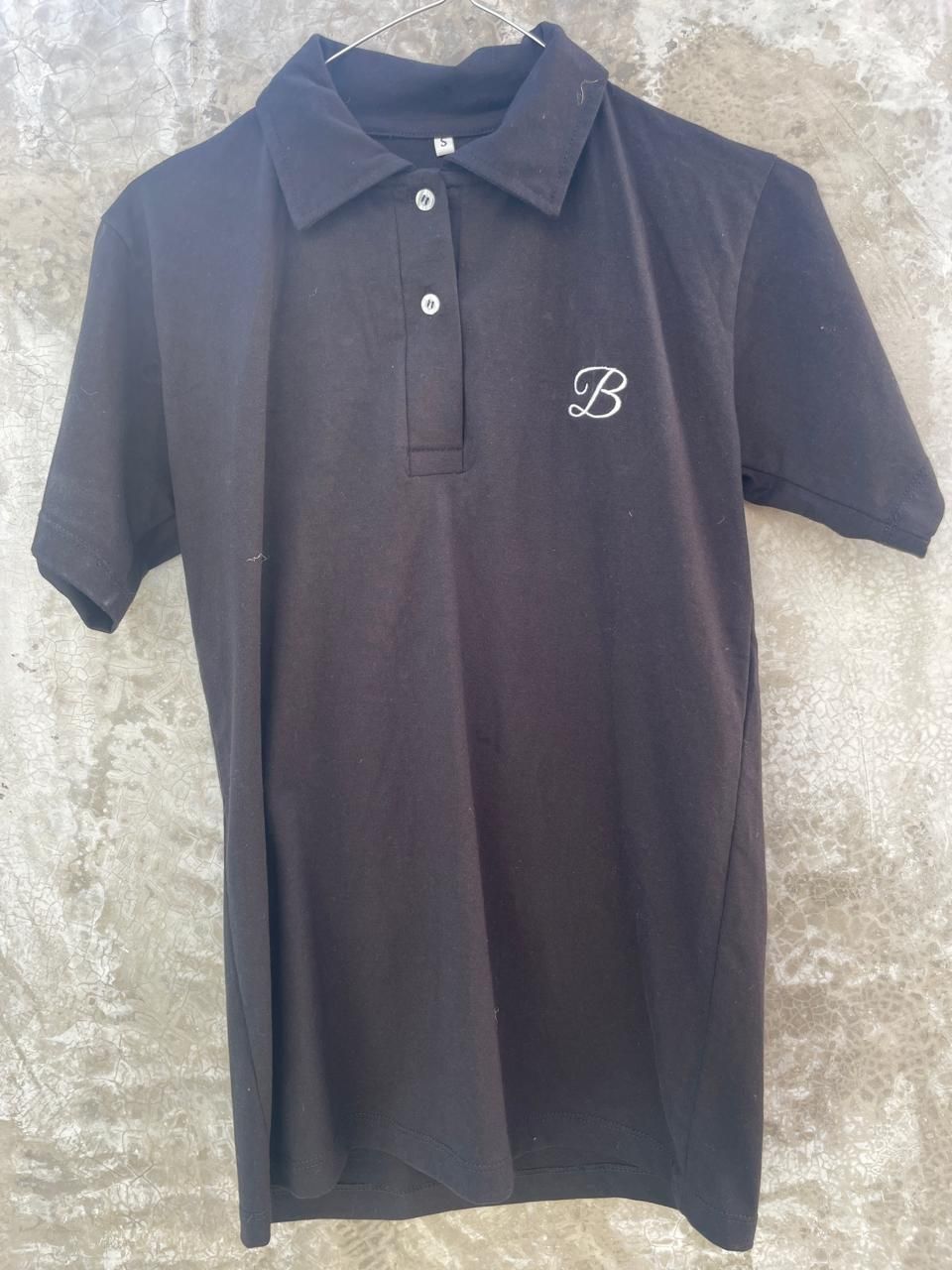 Un polo negro con la letra b.