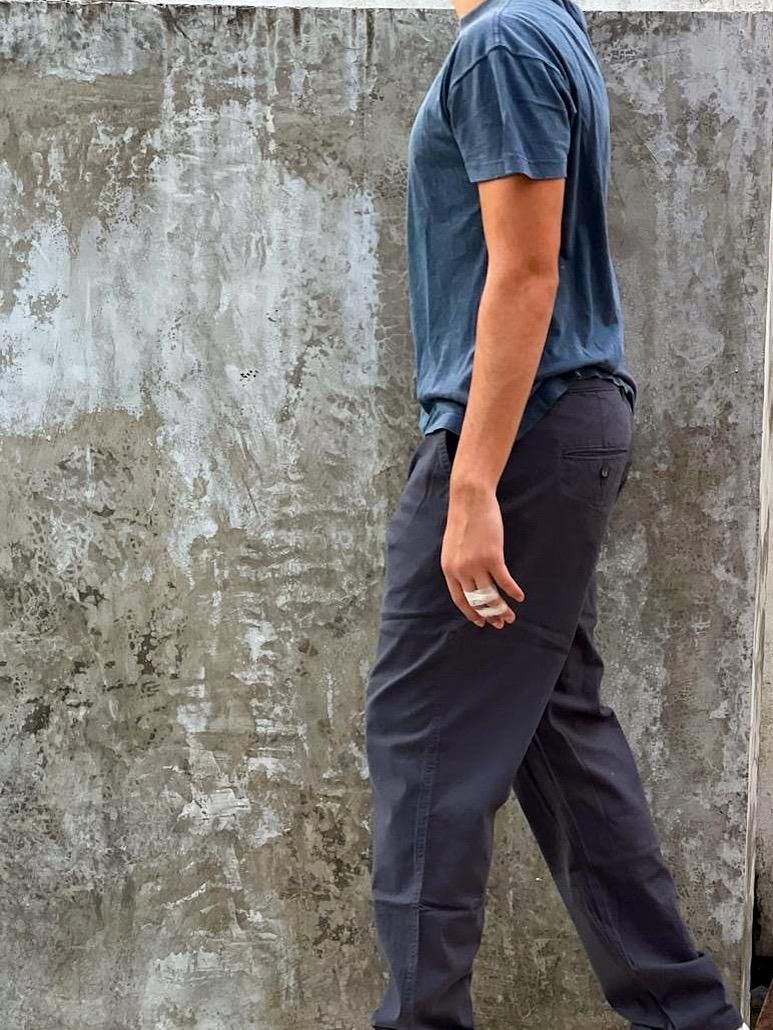 Un hombre con una camiseta azul está de pie con las manos en los bolsillos.