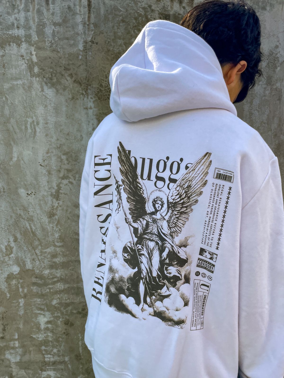 Un hombre que lleva una sudadera blanca con un ángel en la espalda.