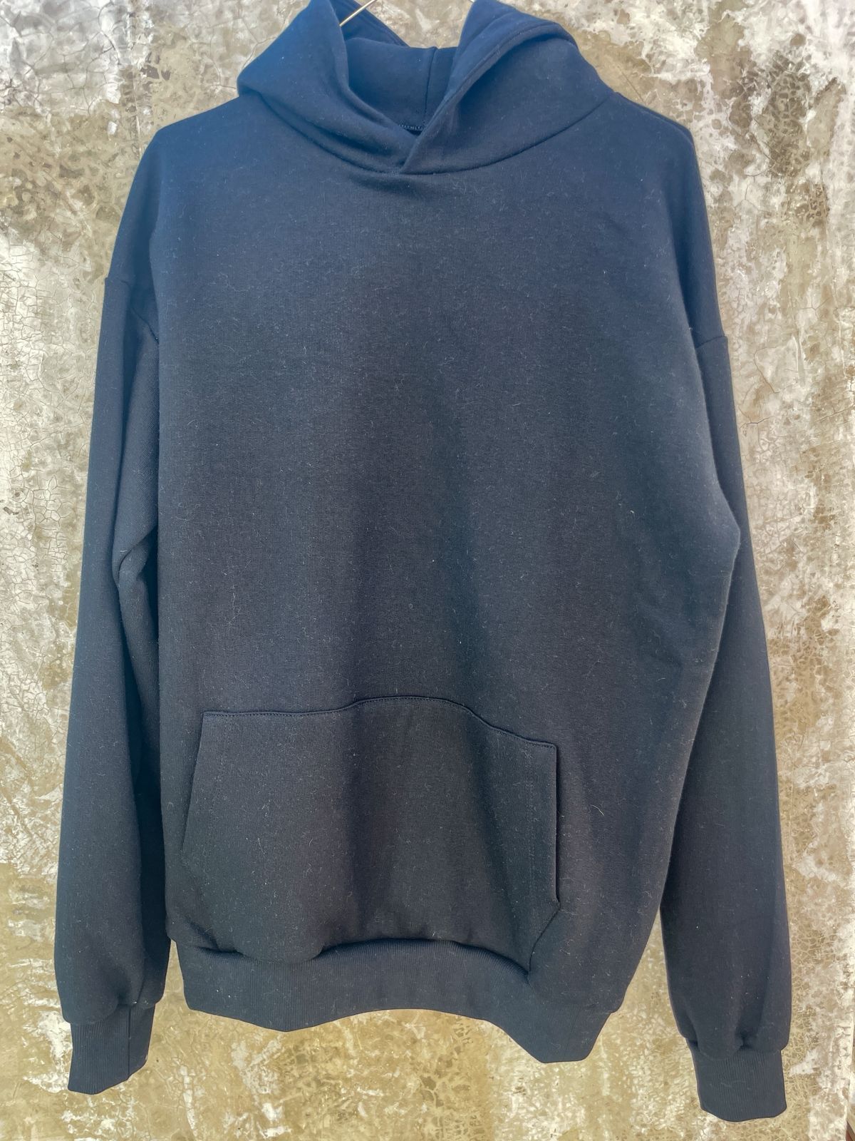 Una sudadera con capucha negra está colgada en una percha en la pared.