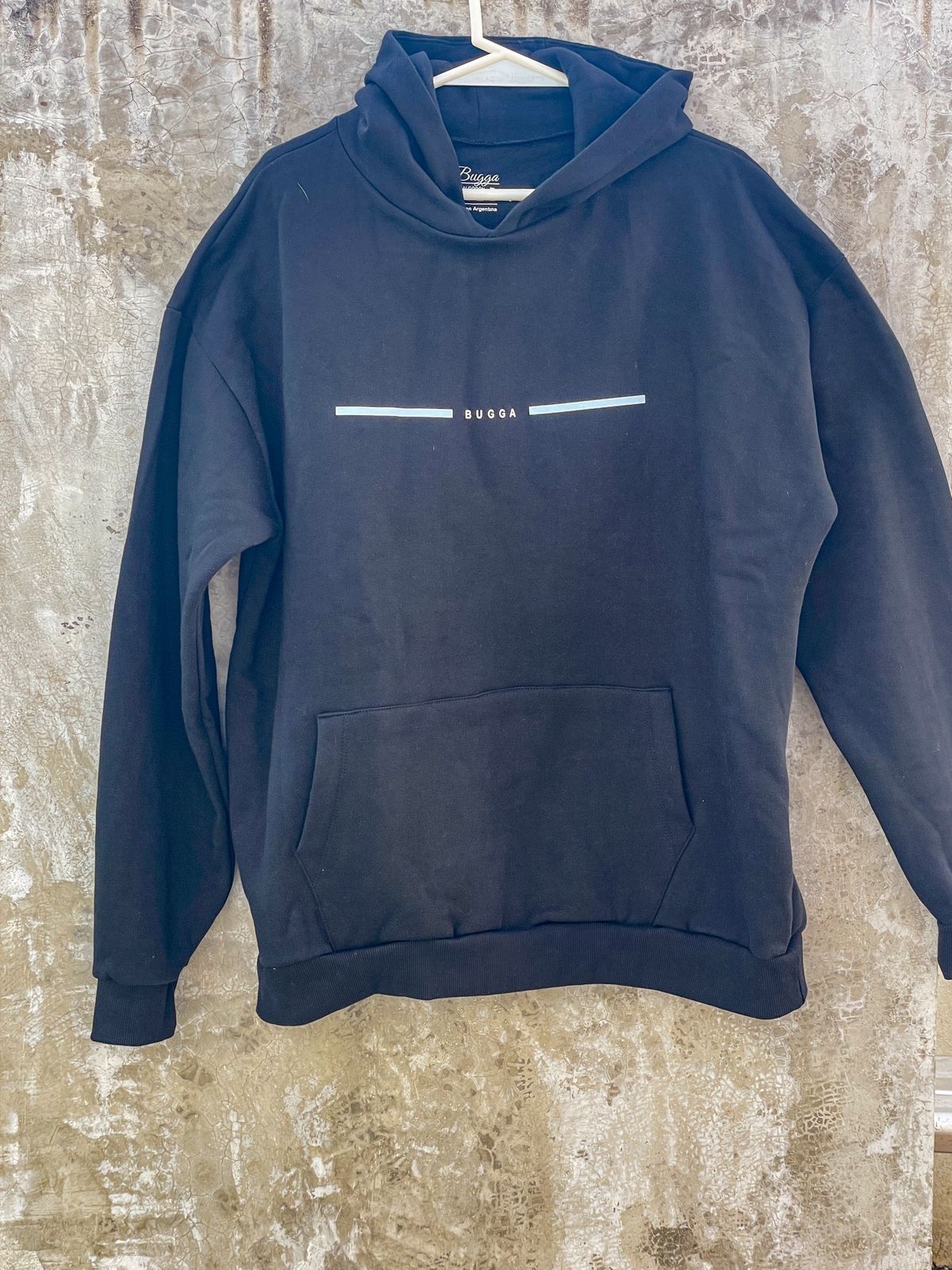 Una sudadera con capucha negra está colgada en una percha en la pared.