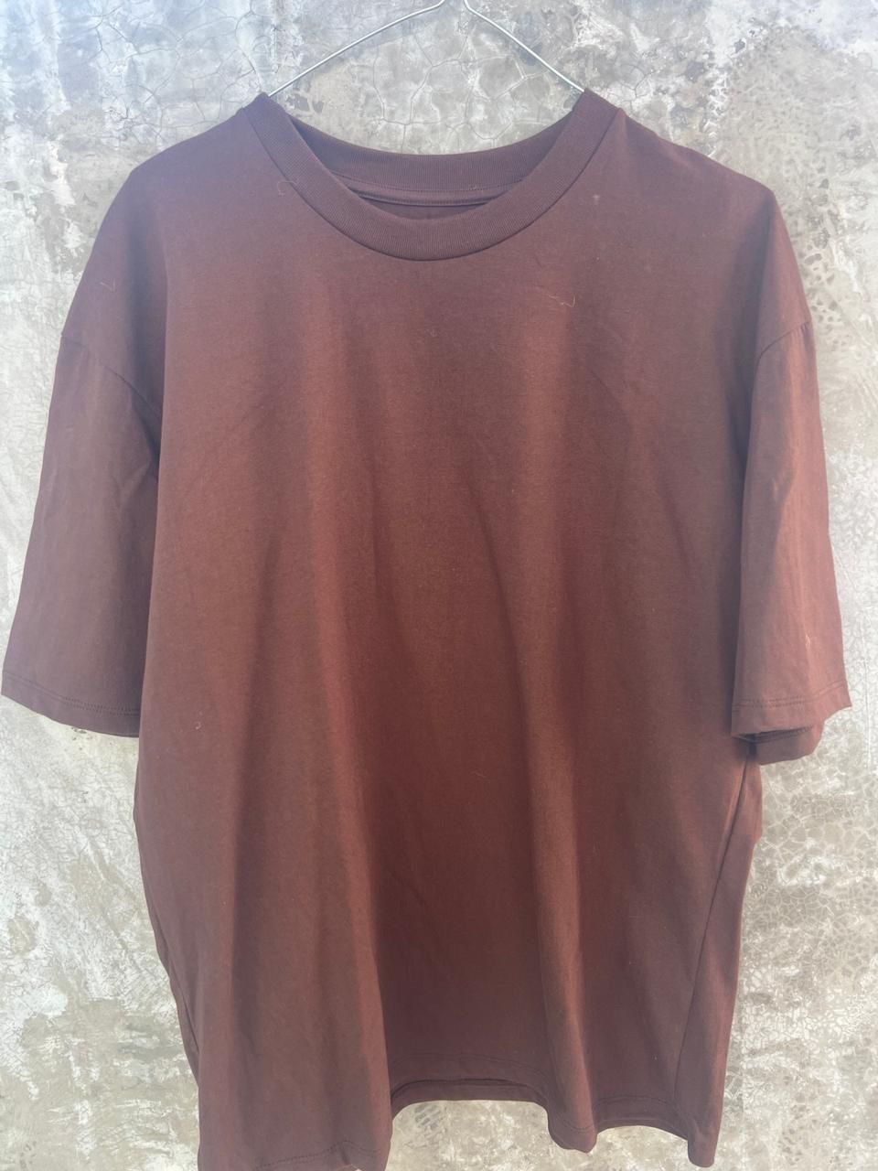 Una camiseta marrón está colgada en una percha.