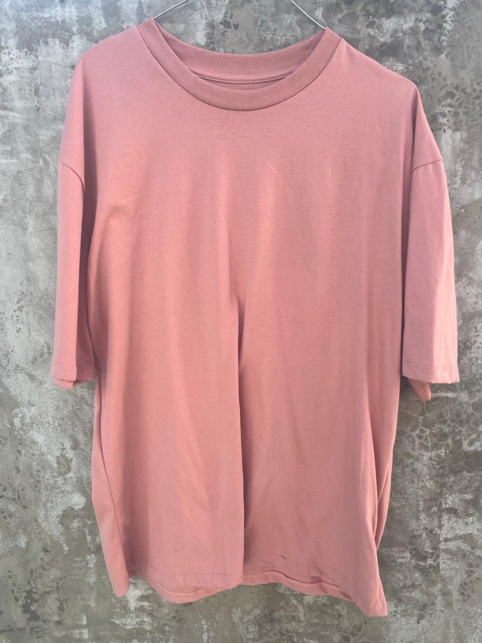 Una camiseta rosa está colgada en una percha.