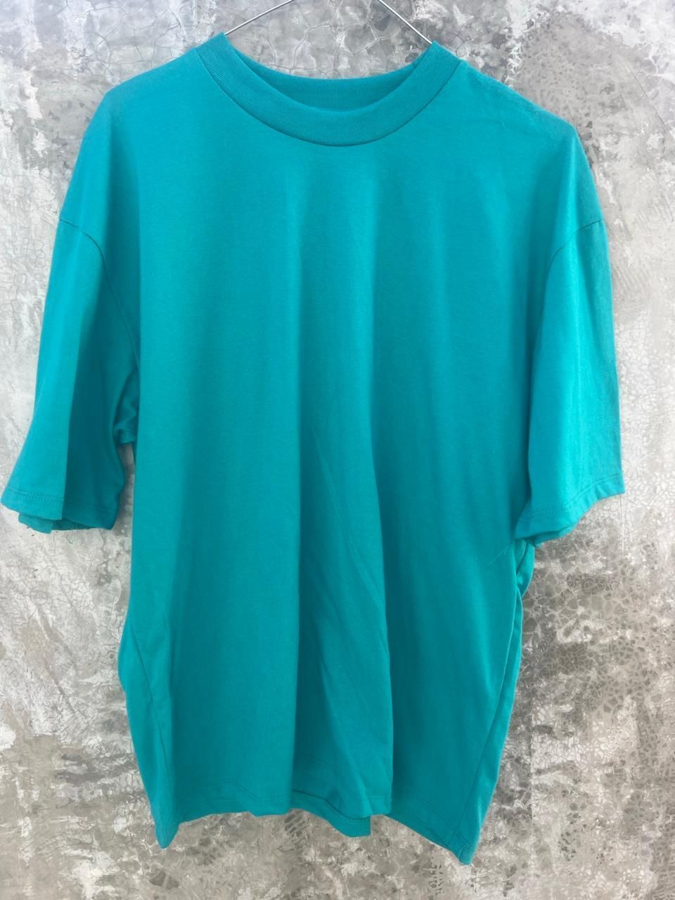 Una camiseta azul está colgada en una percha en una pared.