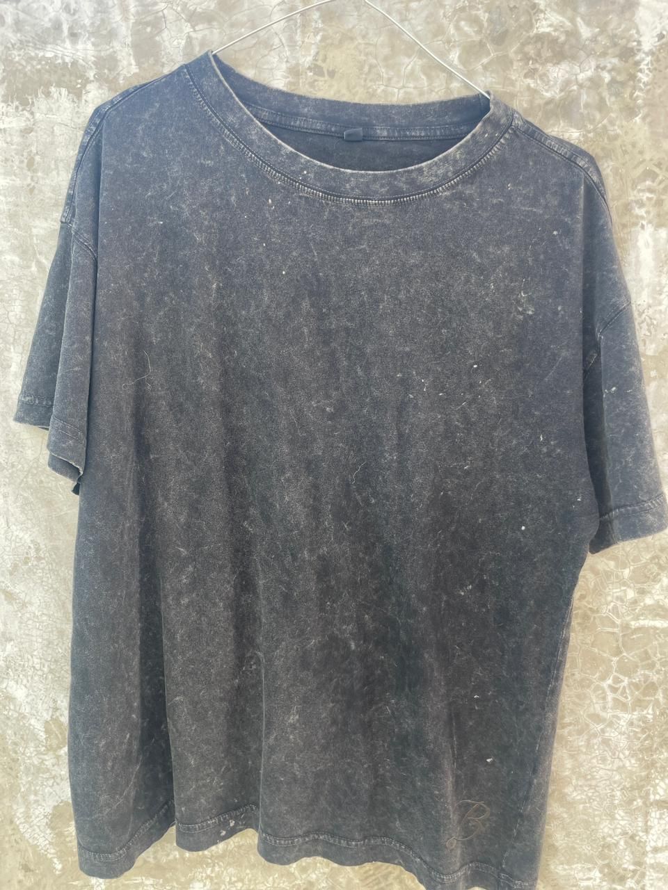 Una camiseta negra está colgada en una pared de hormigón.