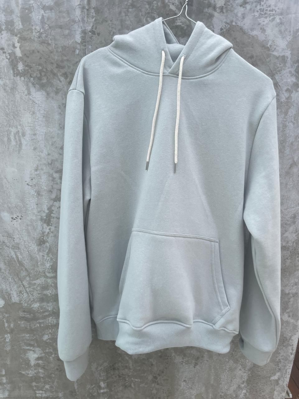 Una sudadera con capucha de color azul claro está colgada en una percha.