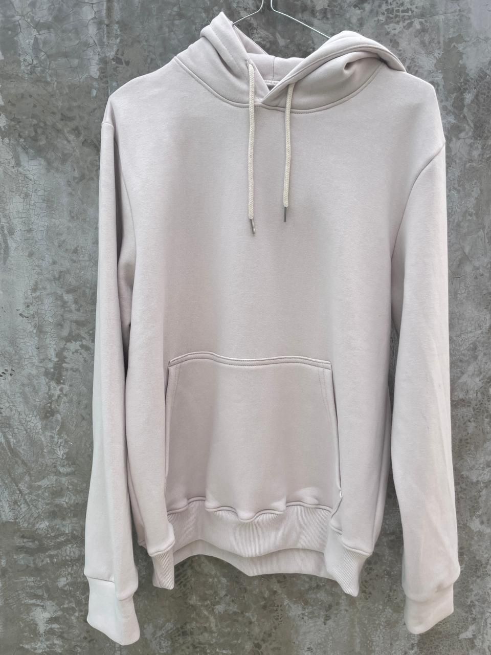 Una sudadera blanca con capucha está colgada en una percha.