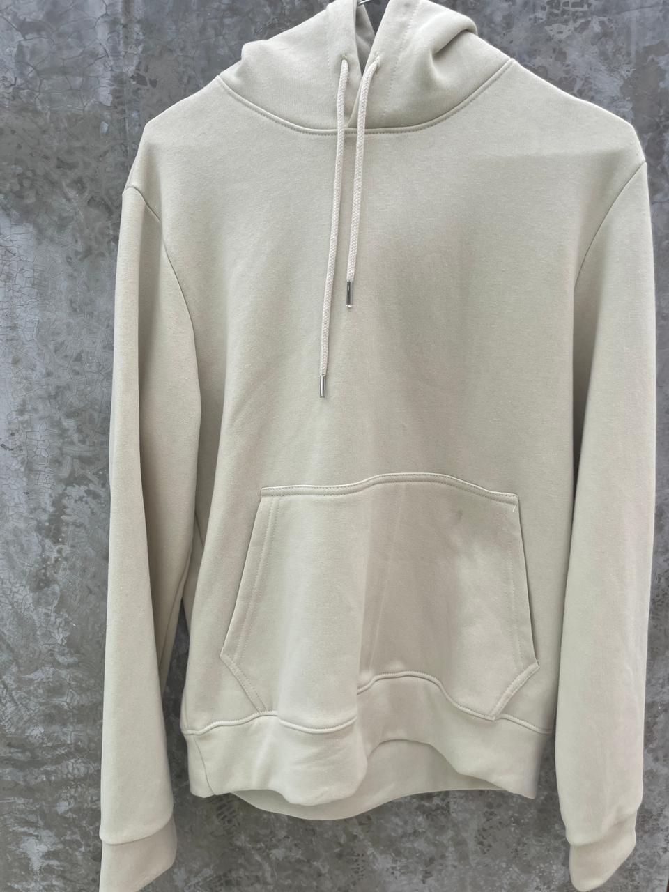 Una sudadera con capucha blanca está colgada en una percha en la pared.