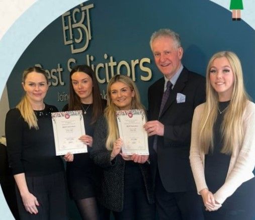 A group of people standing in front of a wall that says best solicitors