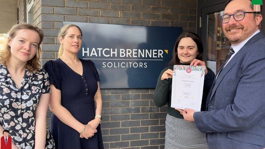 A group of people standing in front of a hatch brenner solicitors sign.