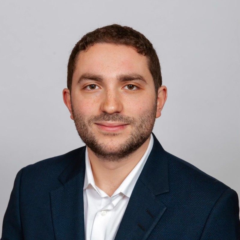A man with a beard wearing a blue suit and white shirt