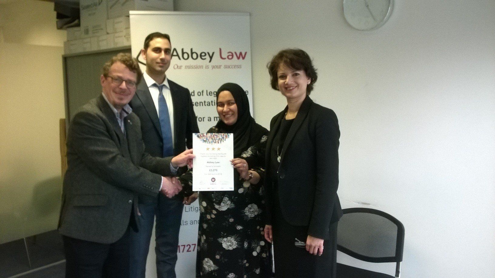 A group of people shaking hands in front of a sign that says abbey law
