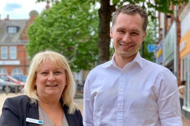 A man and a woman are standing next to each other on a sidewalk.
