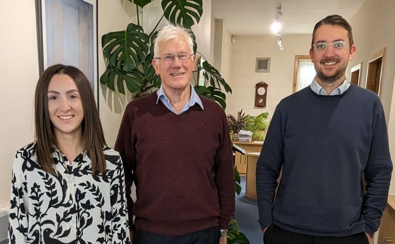 A man and two women are standing next to each other in a room.