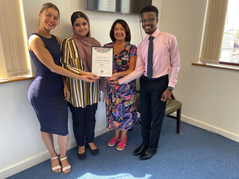 A group of people are standing in a room holding a certificate.