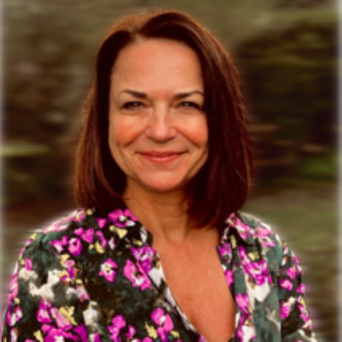 A woman wearing a floral shirt is smiling for the camera