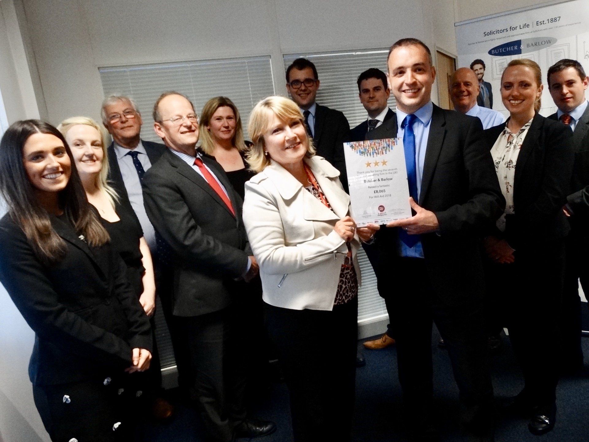 A group of people are posing for a picture and one woman is holding a certificate