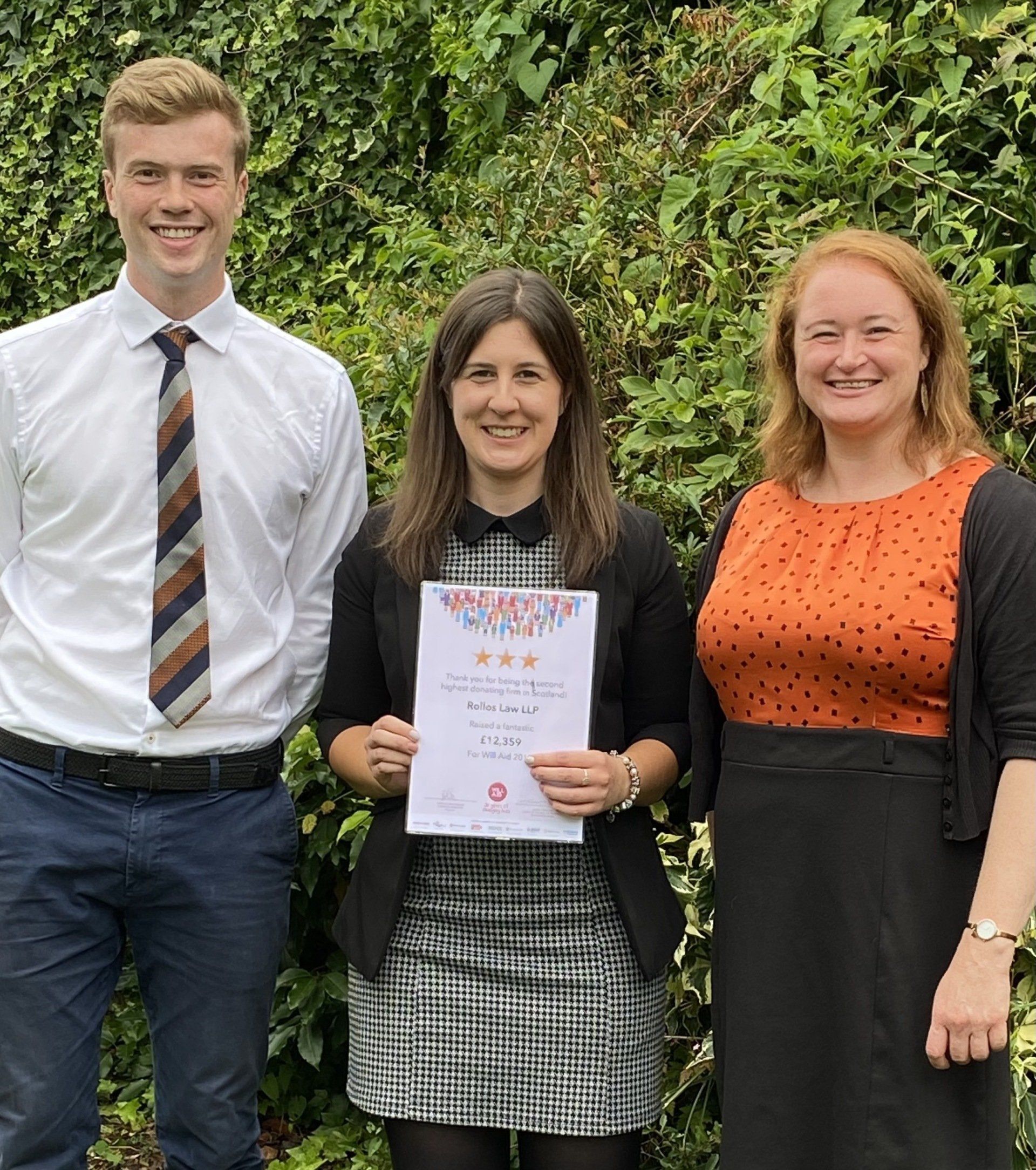 A man and two women are standing next to each other holding a certificate.