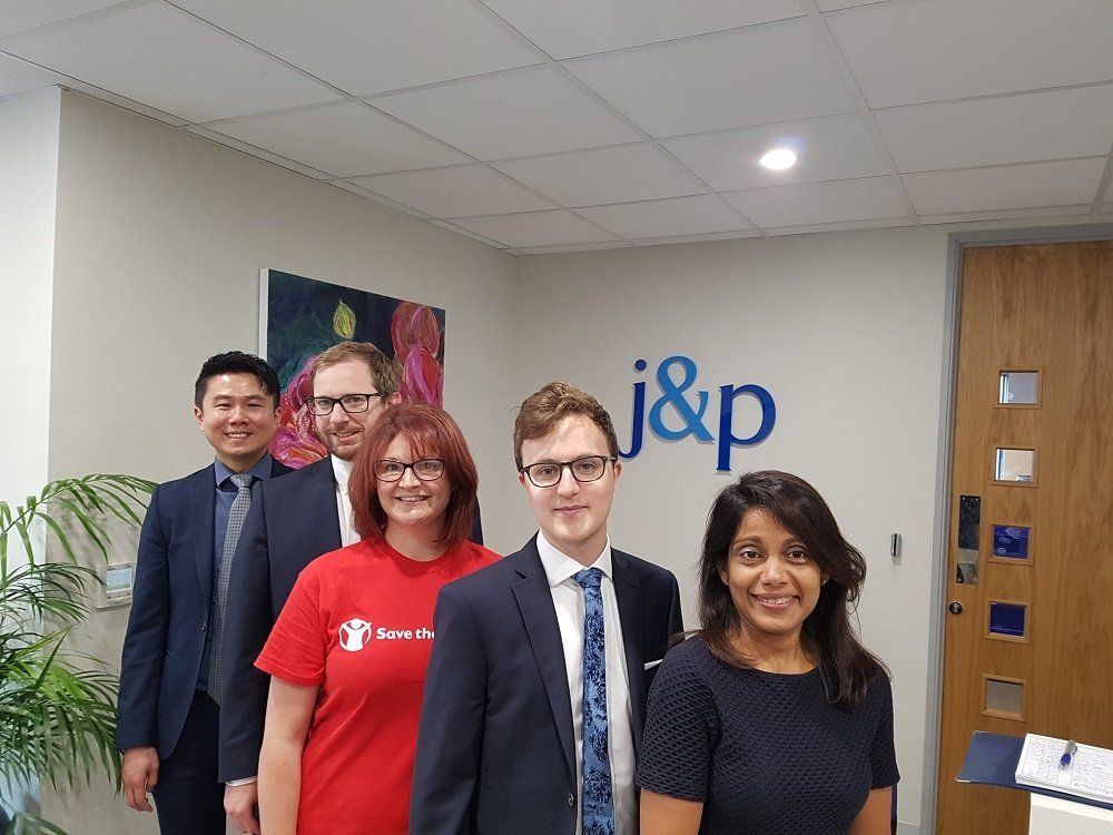 A group of people are posing for a picture in front of a sign that says j & p.