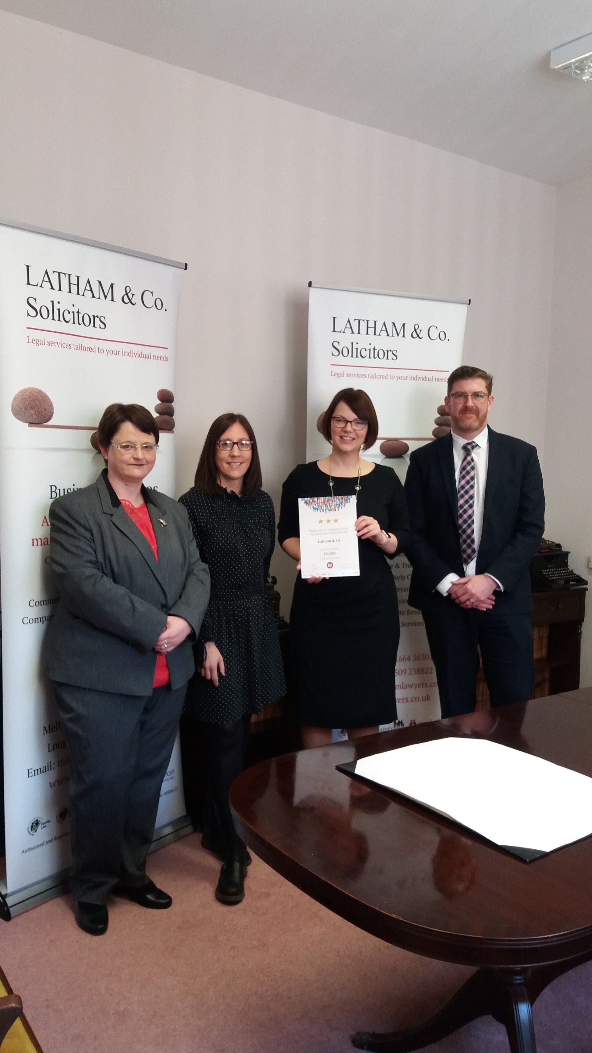 A group of people standing around a table holding a certificate.