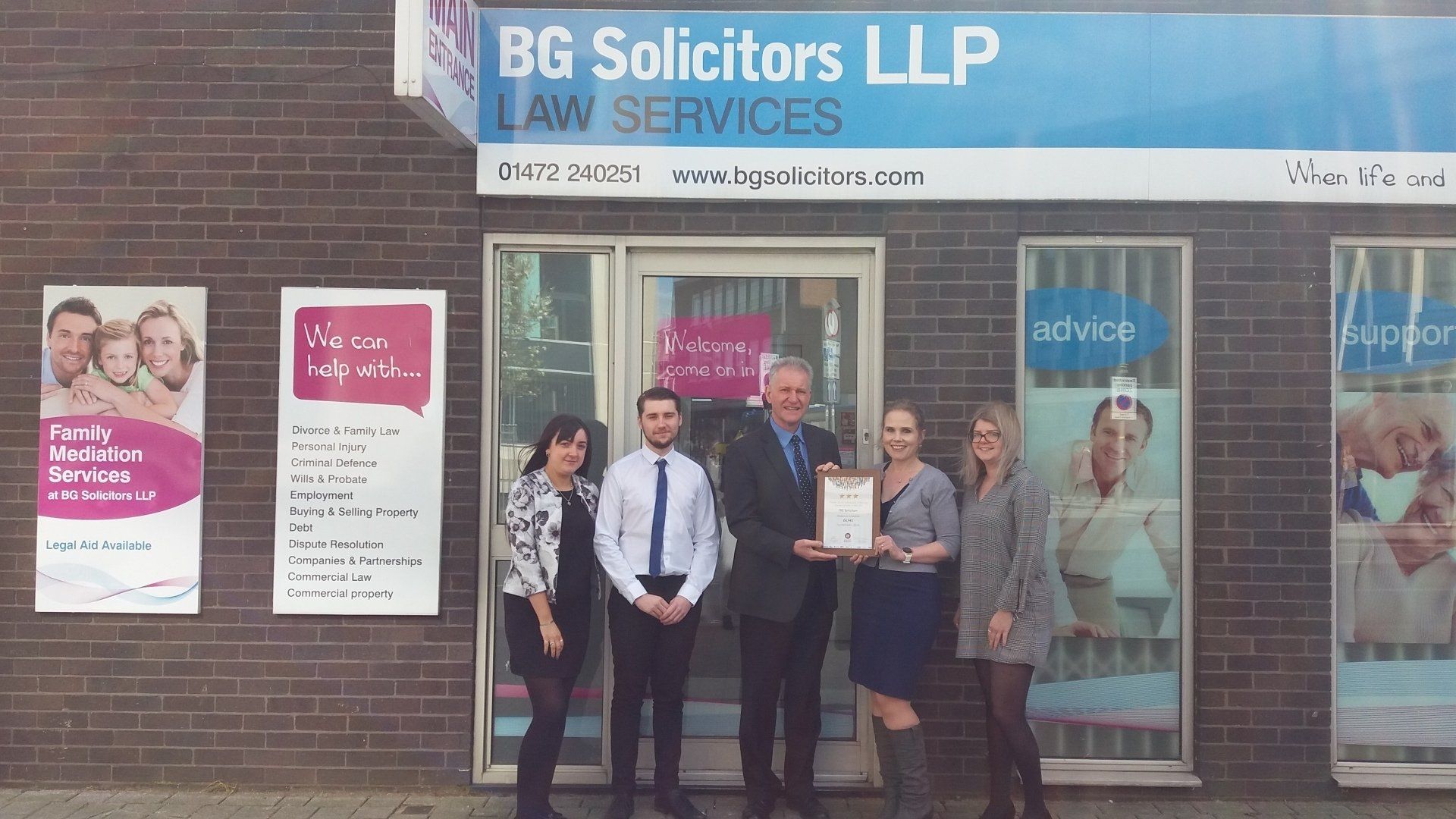 A group of people standing in front of a bg solicitors llp law services building