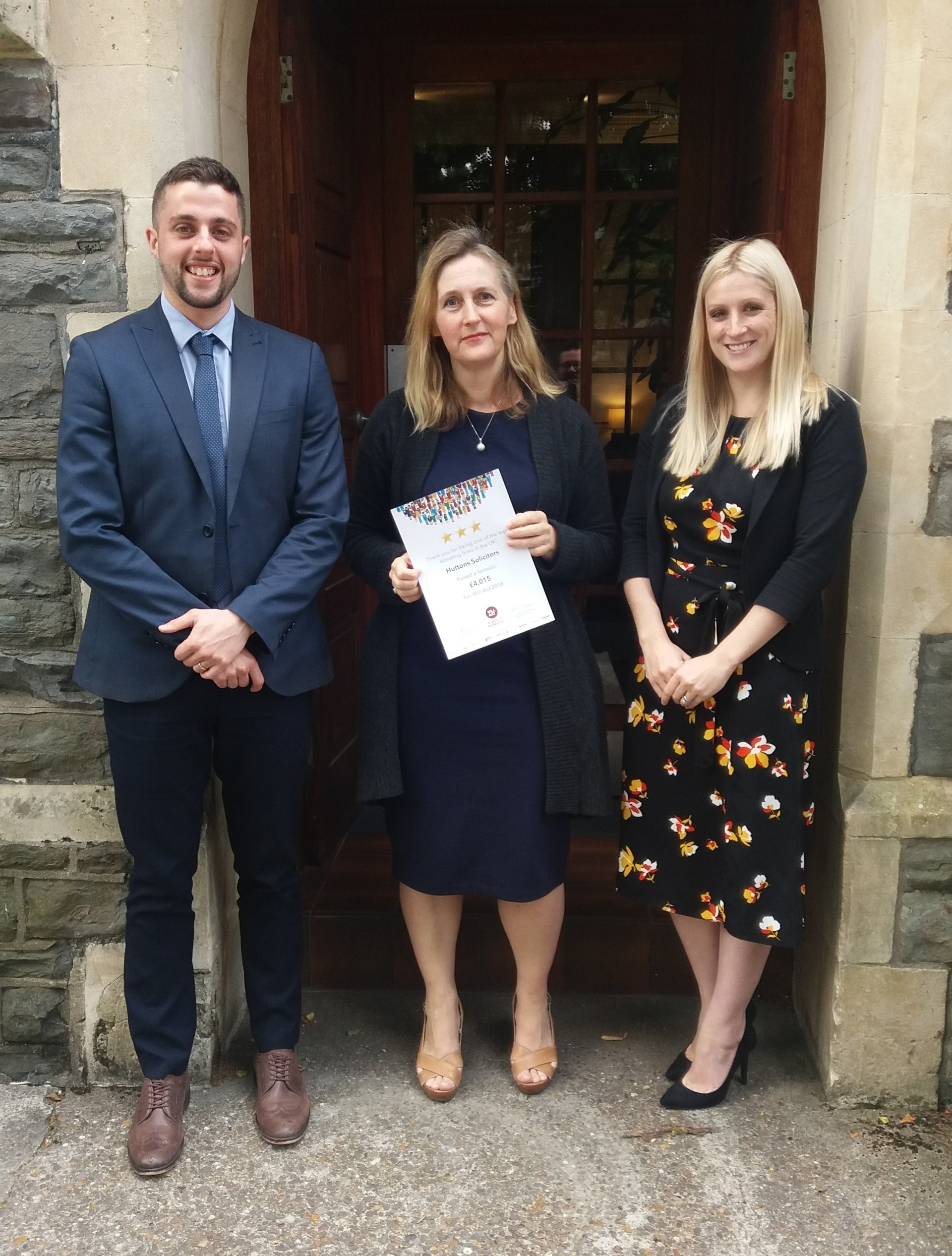 A man and two women are standing in front of a building.