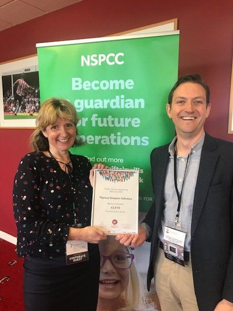 A man and a woman are standing in front of a sign that says nspcc