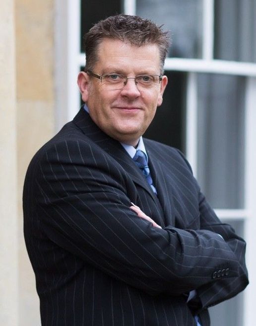 A man in a suit and tie with his arms crossed