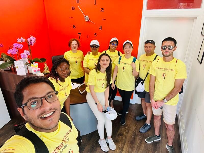 A group of people wearing yellow shirts are posing for a picture in front of a clock.