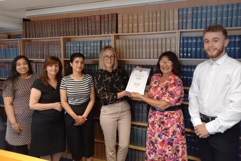 A group of people are standing in front of a bookshelf holding a certificate.